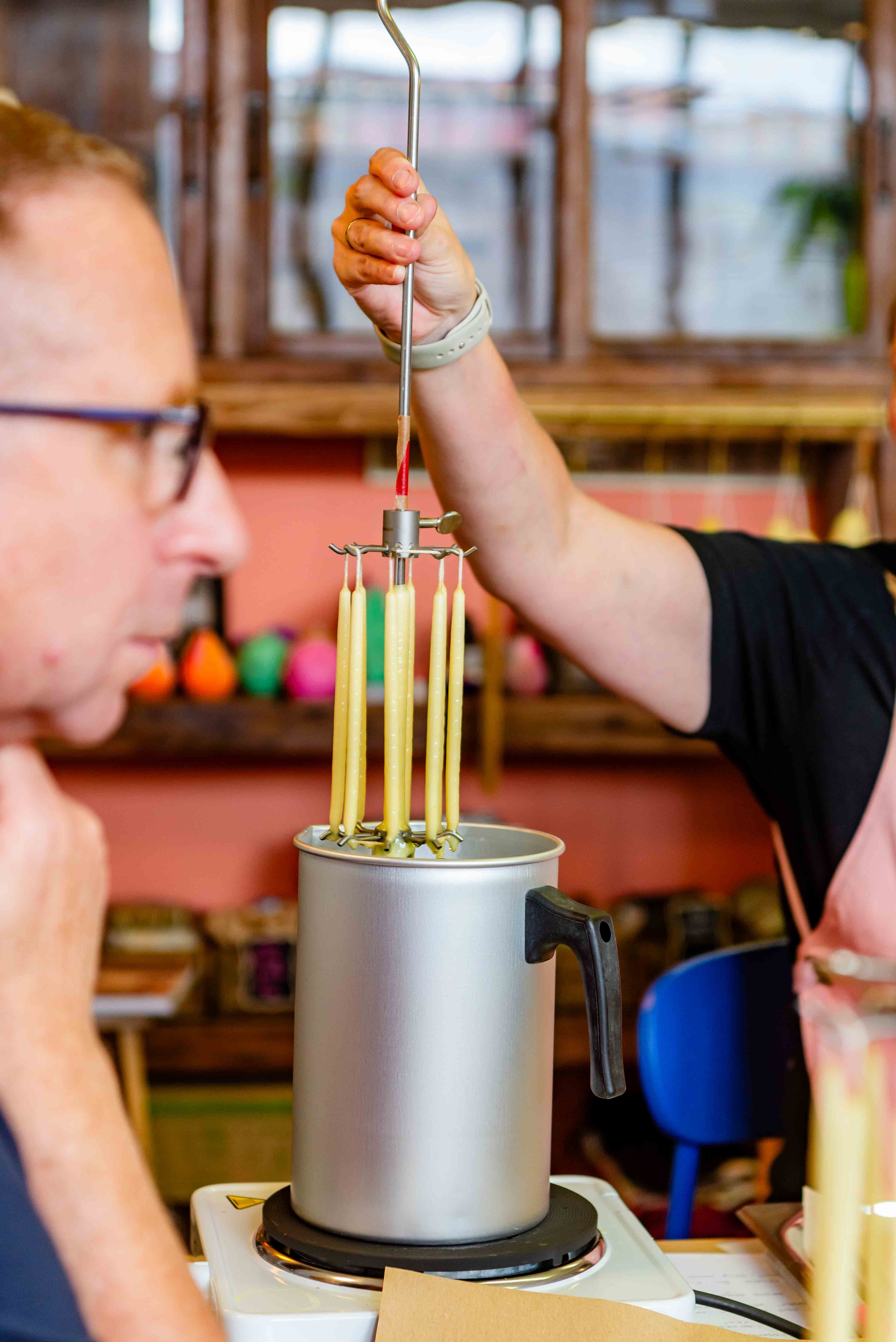 Beeswax candles being dipped ina nd out of a jug in the wax atelier surrey studio