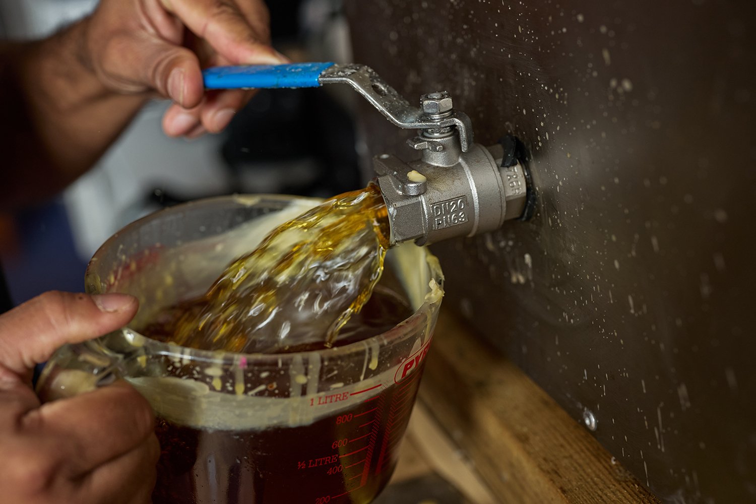 Pouring beeswax out of the melter as it splashes out.